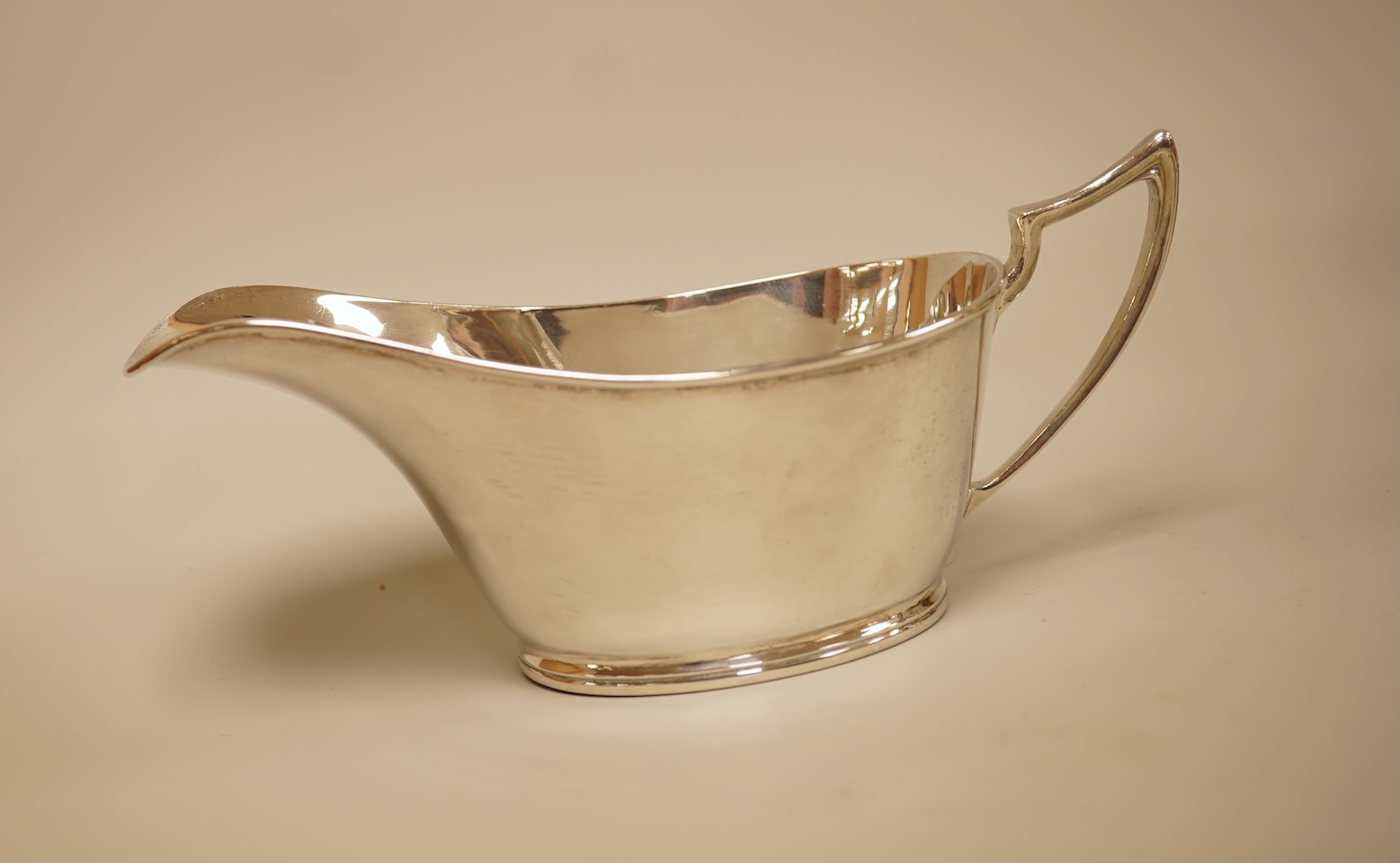 A pair of George V silver sauceboats by Walker & Hall, Sheffield, 1929/30, length 17.9cm together with a George V silver sauceboat with flying scroll handle, William Comyns & Sons Ltd, London 1926, 16.4oz.